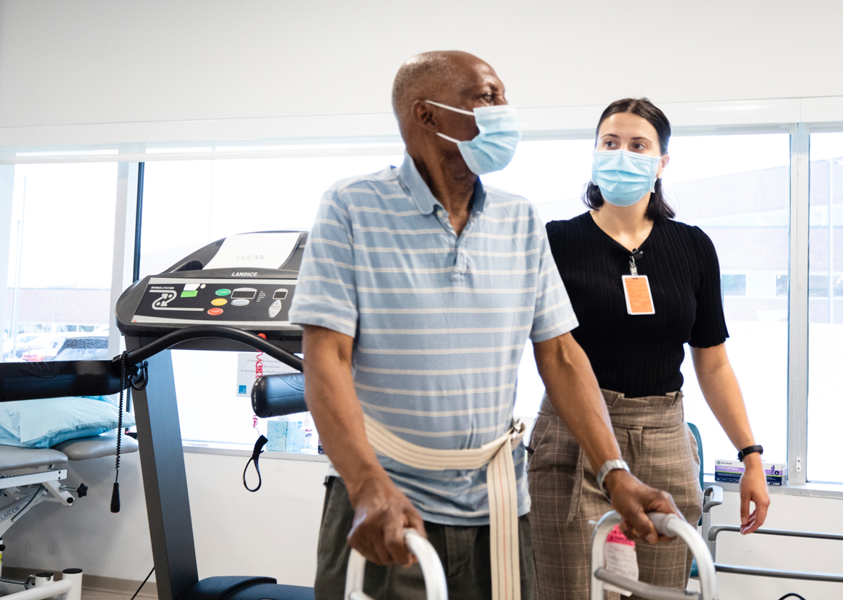 A man using a walker, working with a physical therapist 