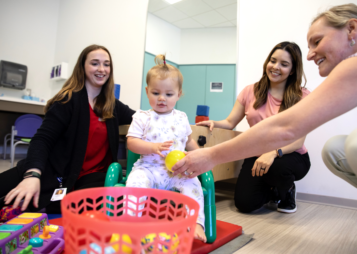 Several women playing games with a toddler 