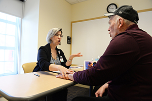 a woman speaks across the table to a man 