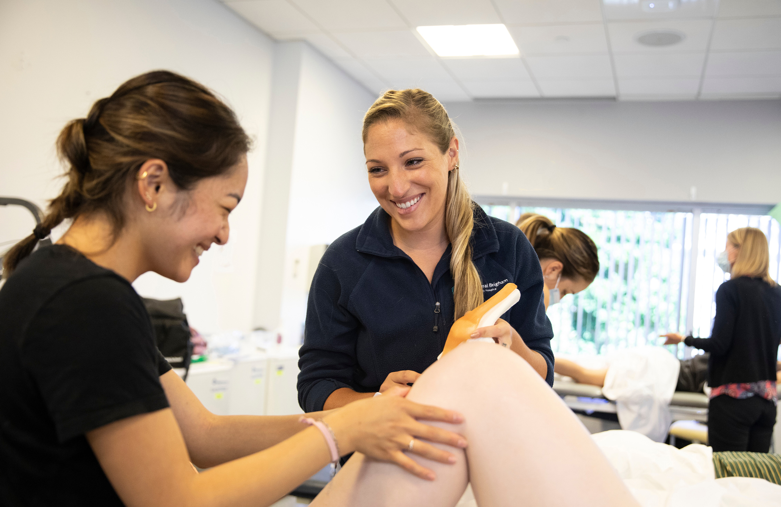 two students look at a person's knee and compare it to a plastic model of a knee