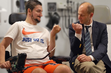 man in suit bends his arm at the elbow along with a man in a wheelchair