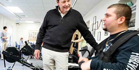 man talks to another man on a recumbent bike