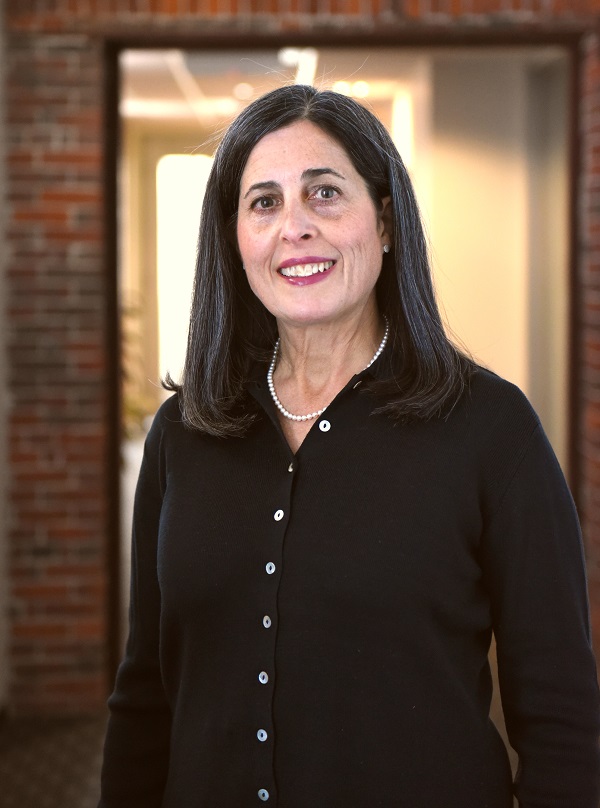 allison wears a black cardigan and pearls