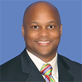 thaddeus wears a dark suit and a colorful tie