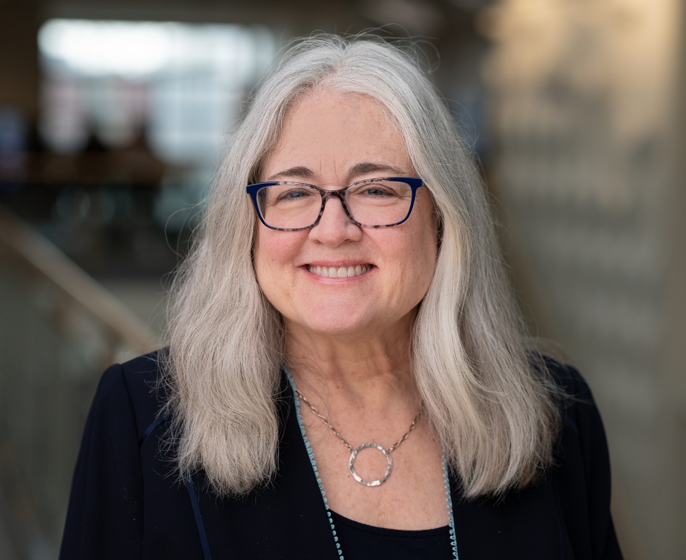 susan has shoulder length grey hair and blue tortoiseshell glasses