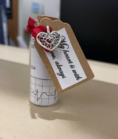 photo of a tiny bottle with a red ribbon and silver heart charm that says my heart is with you always