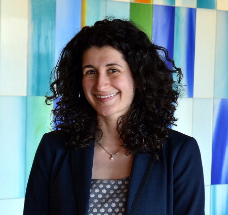 yelena wears a blue blazer and has dark wavy hair