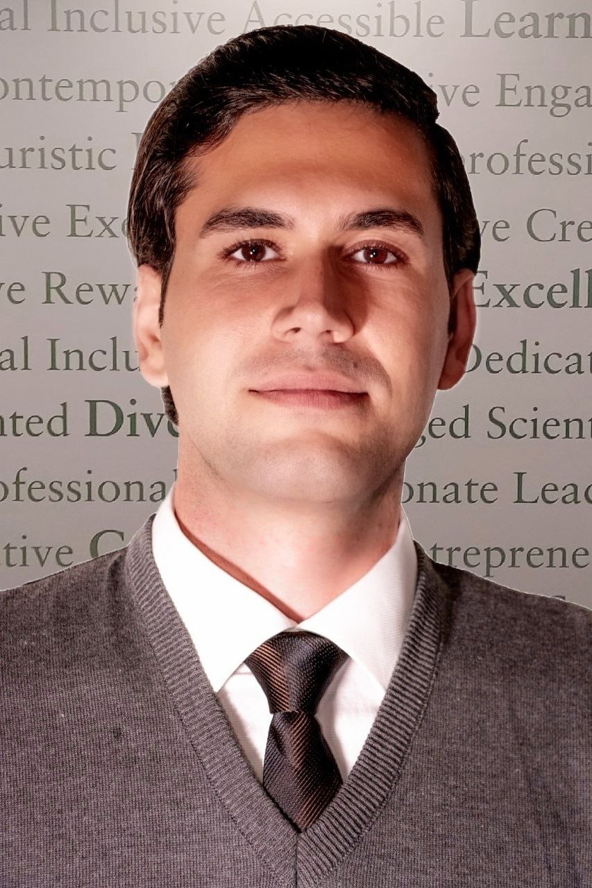 ehsan is lit from below and wears a tie and sweater over a white collared shirt