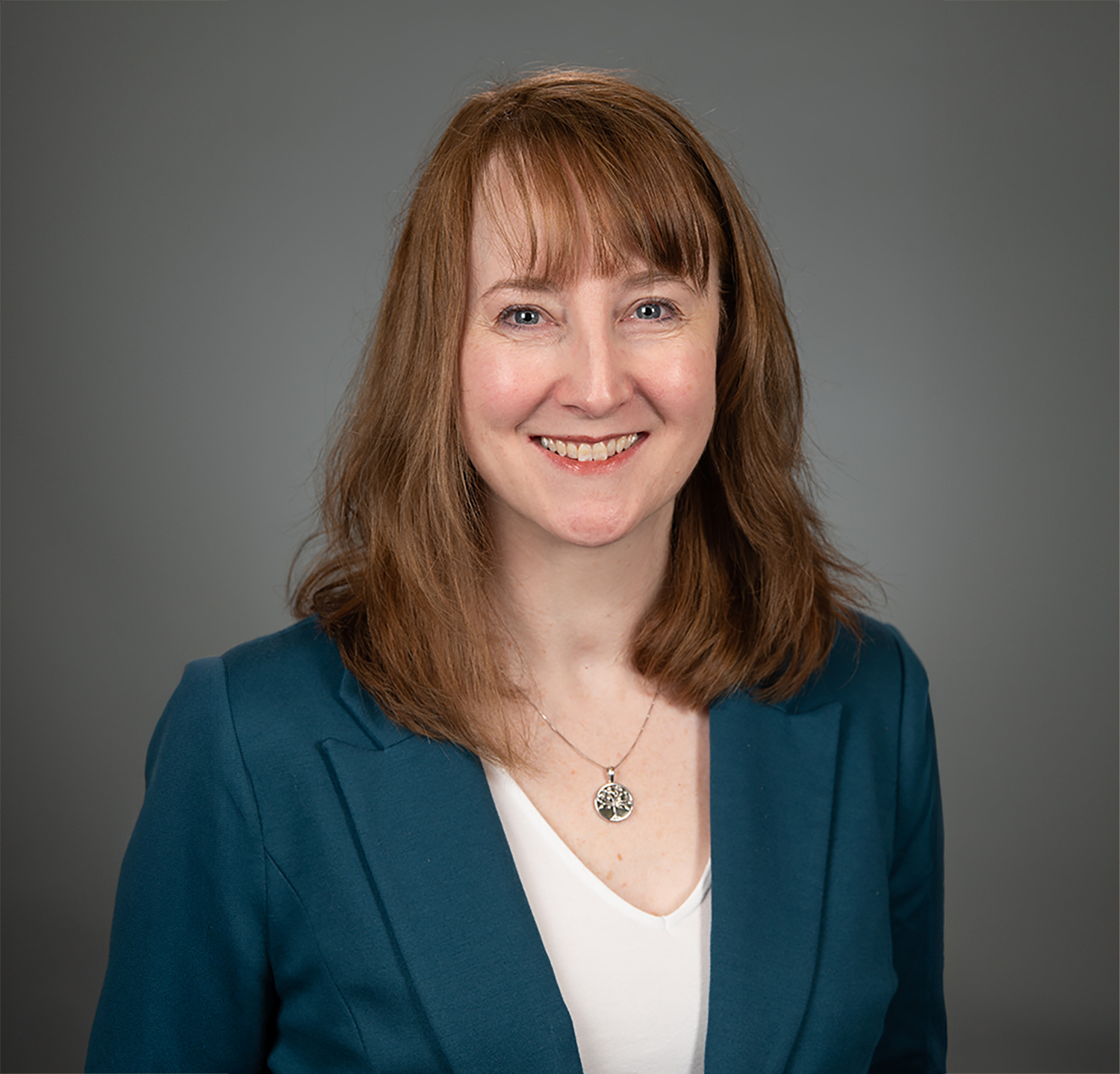 kathy wears a dark teal jacket and has strawberry blonde shoulder length hair