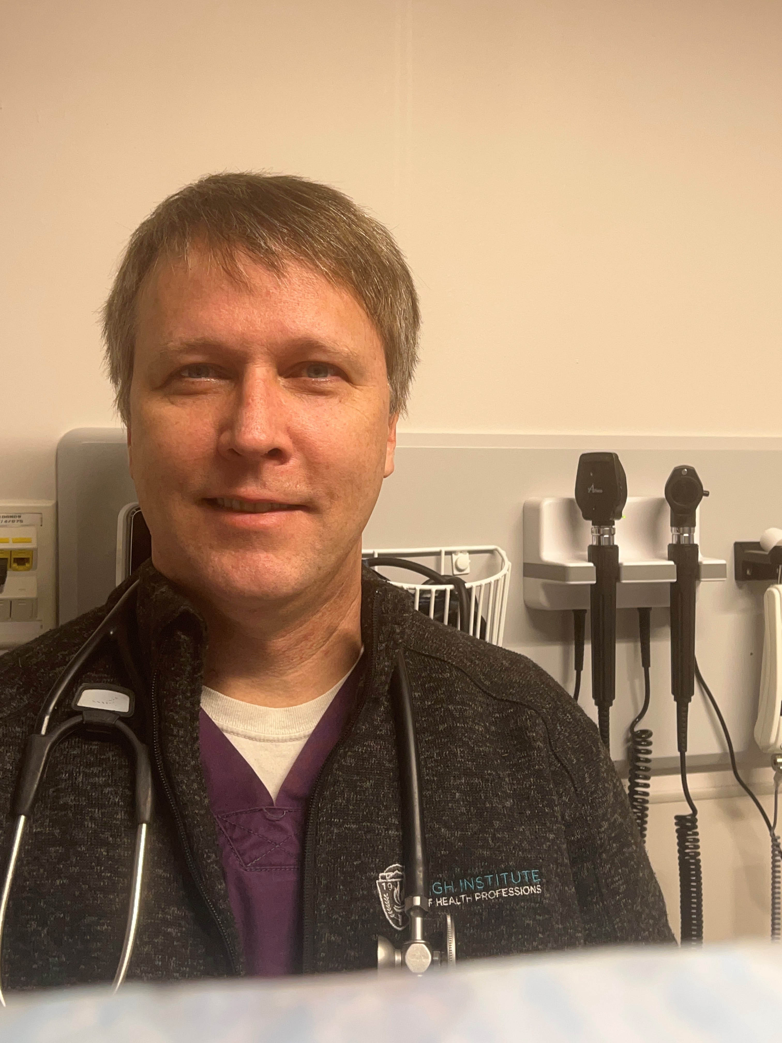 man in front of some otoscopes on the wall