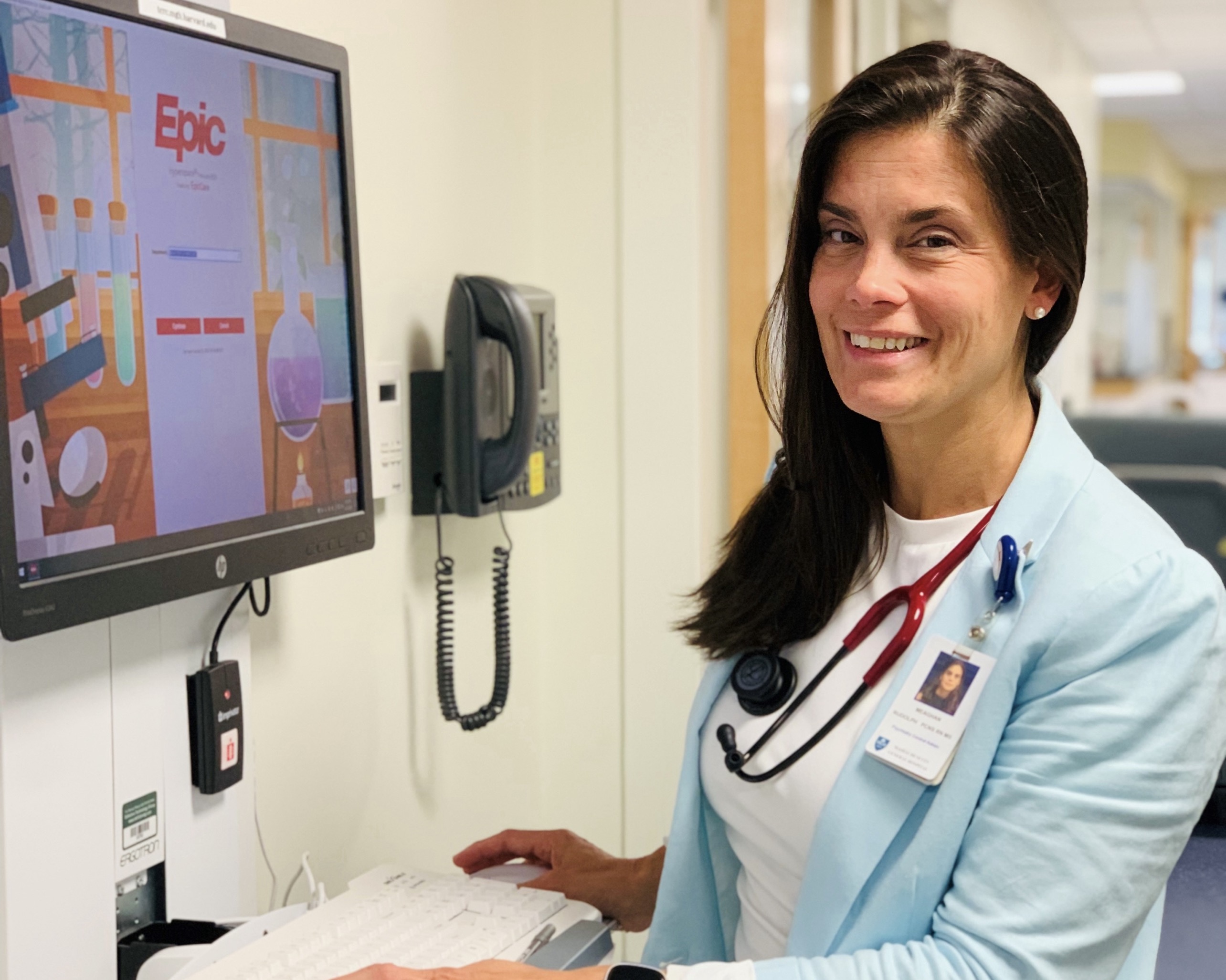 woman at computer that is attached to a hospital hallway wall