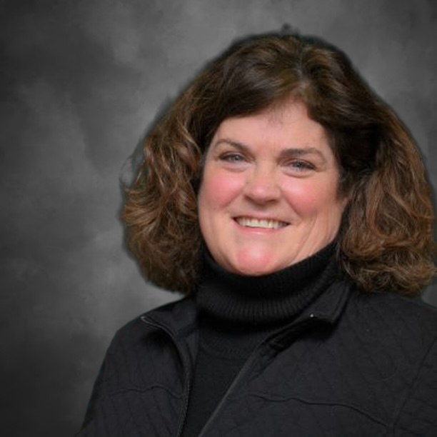 Deanna Denault has shoulder-length brown hair and is wearing a black turtle neck