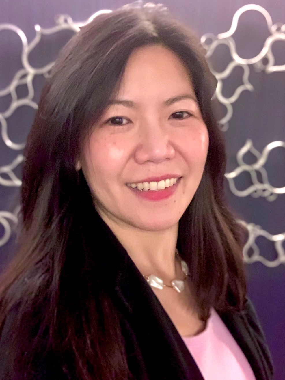 Jenny Ling Hui Loh has long dark brown hair and is wearing a black blazer and pink shirt