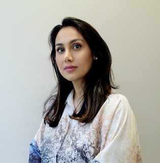 Reem Alansari has long dark brown hair and is wearing a white and blue top.