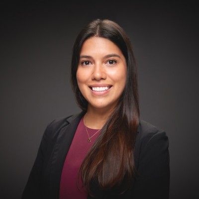 Daniela Diaz Caro has long, straight brown hair. She is wearing a black blazer and a burgundy top.