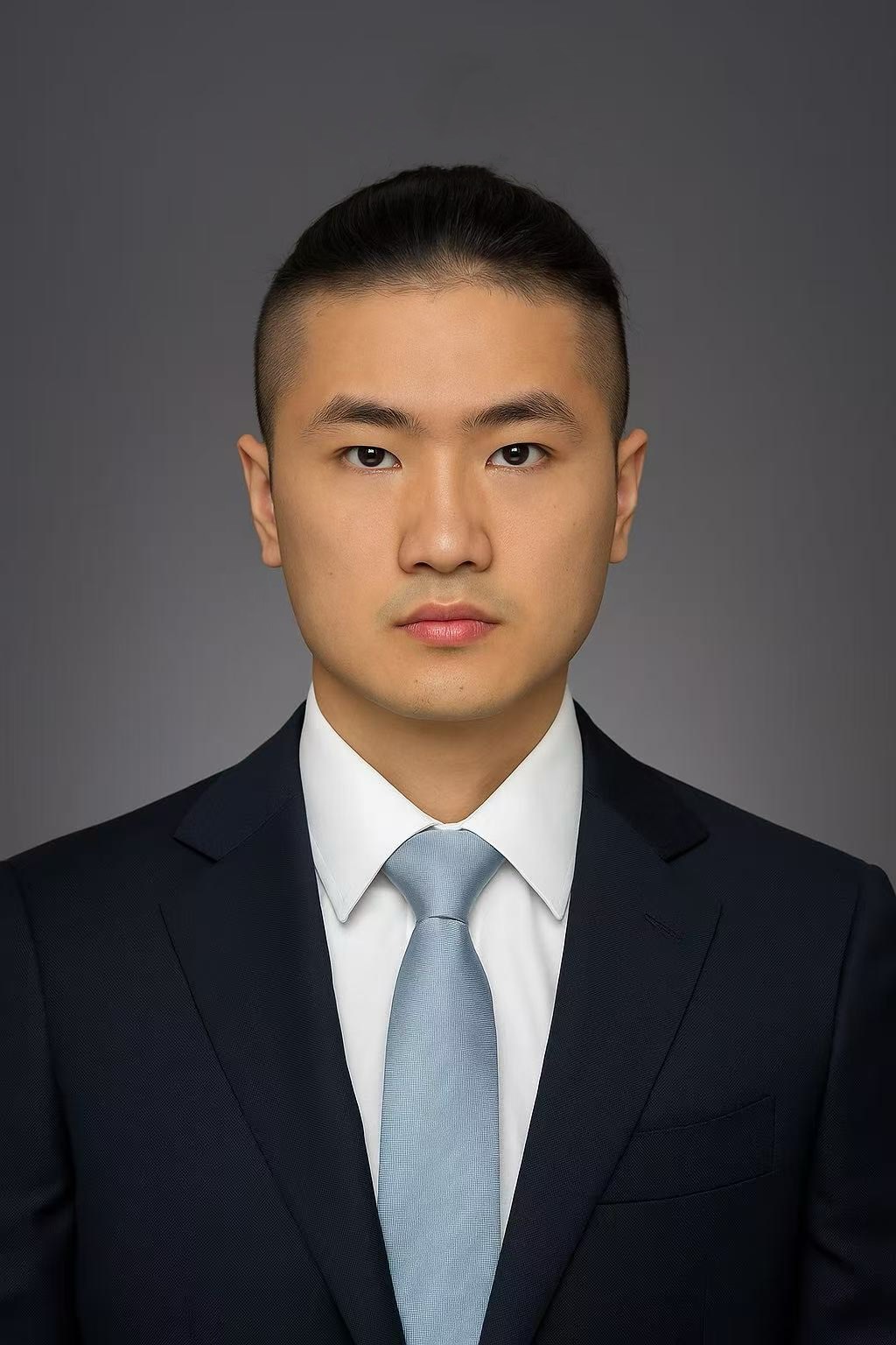 Headshot of Man wearing a white shirt, blue necktie, and black jacket against a solid dark gray background.