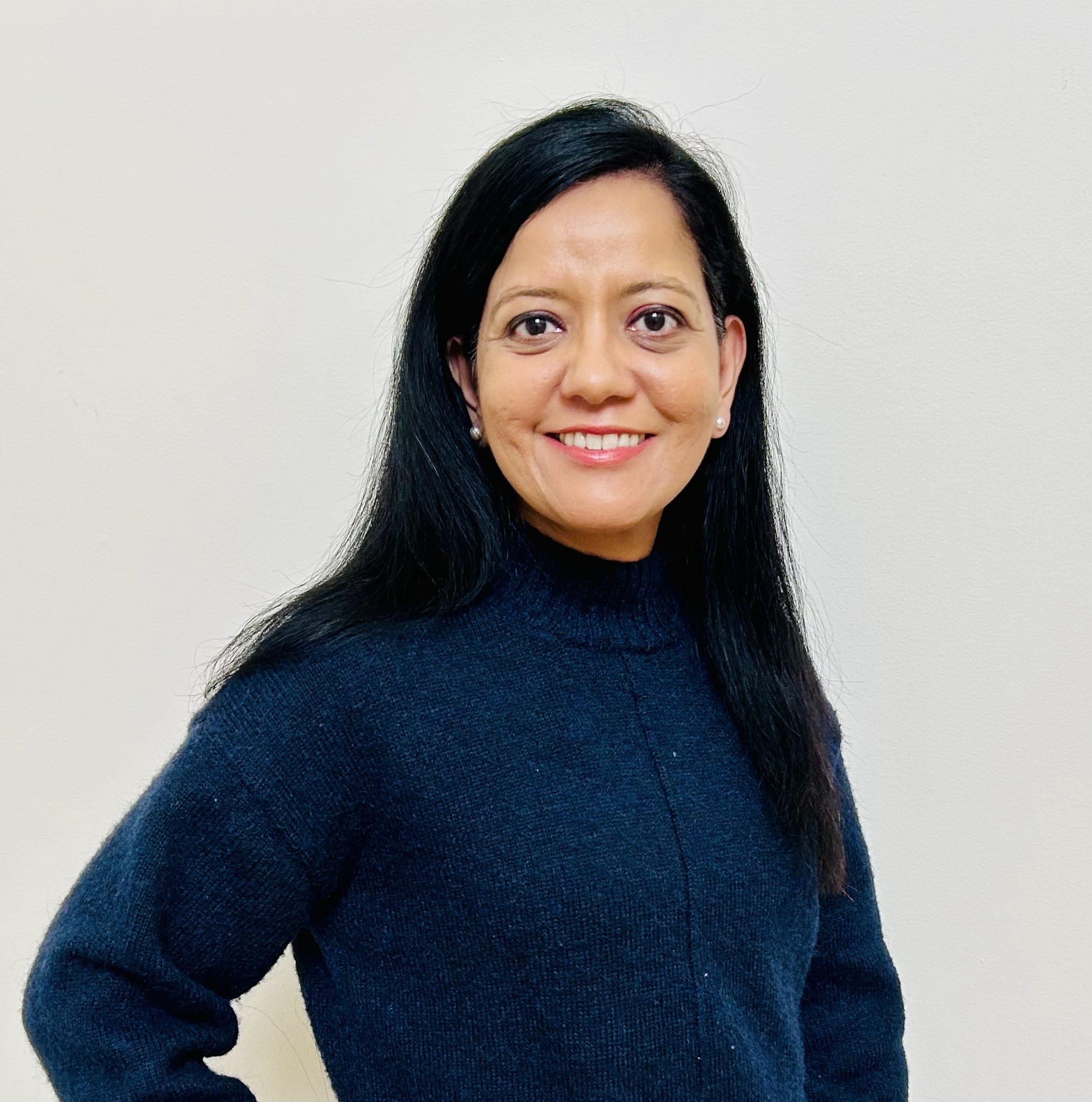 Headshot of woman with long black hair wearing a blue long sleeve shirt against a white background