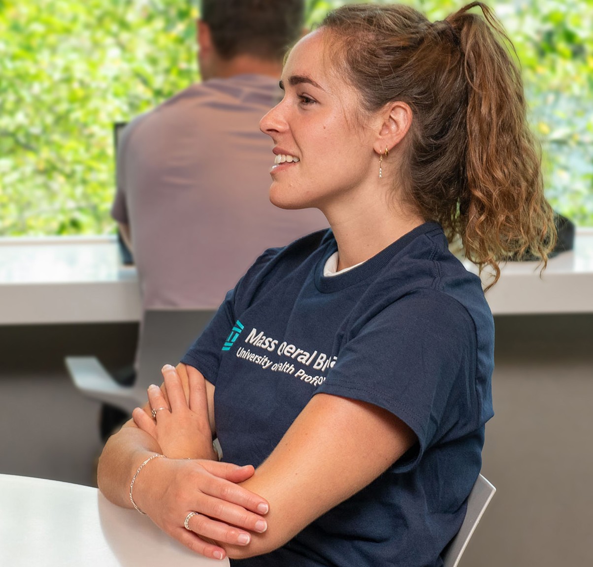 smiling woman in ponytail sits at a desk