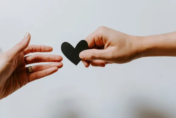 one hand handing a heart to another