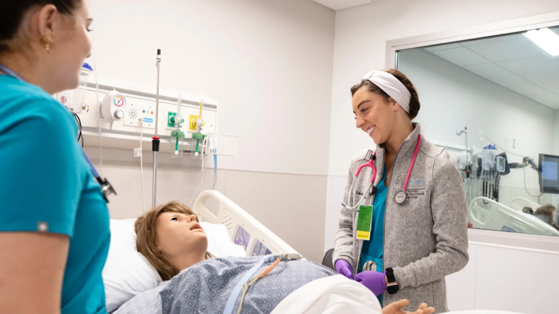 Two medical professionals standing around a patient laying in a hospital bed