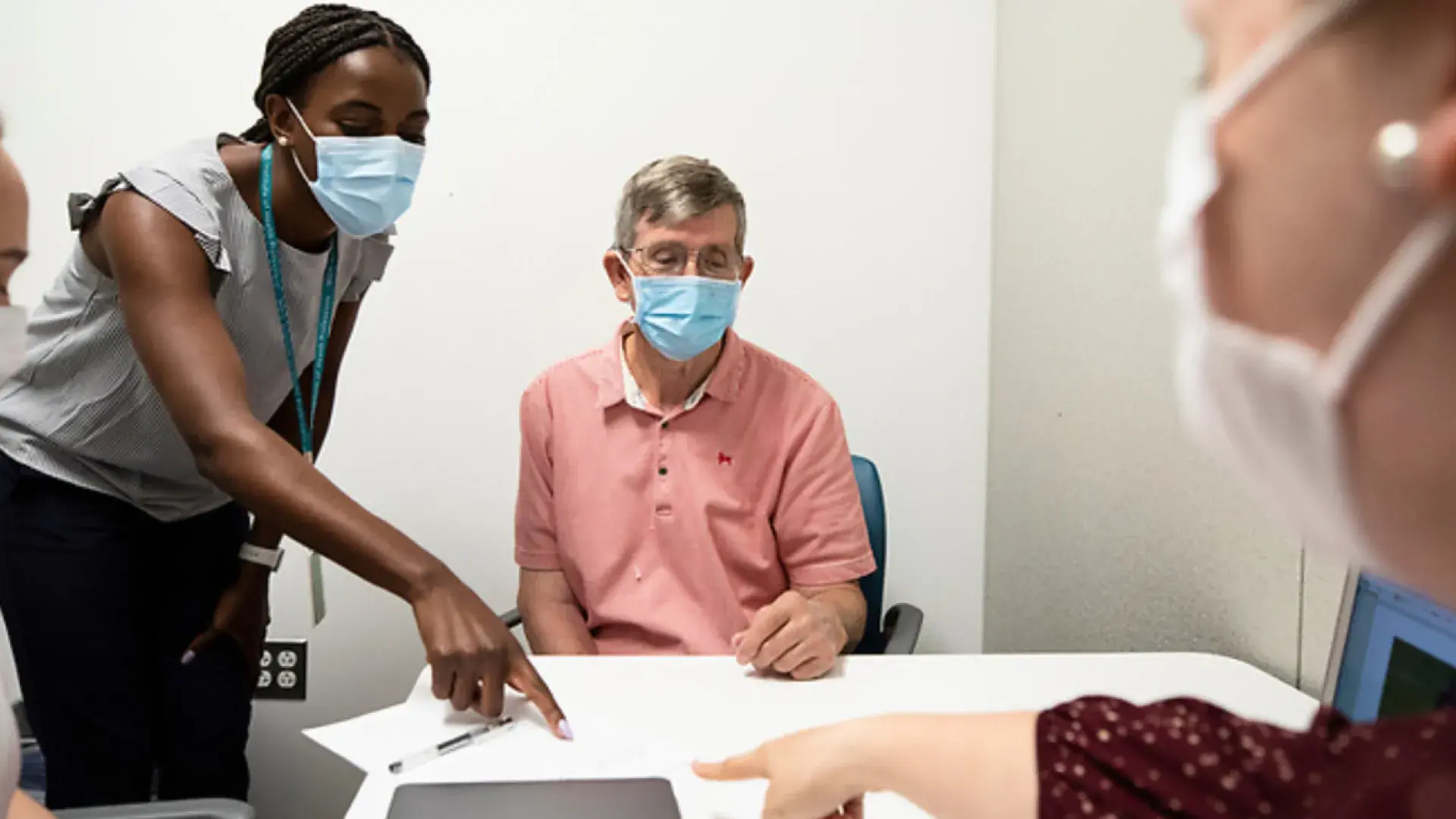 Two medical professionals pointing at a piece of paper while a patient observes 