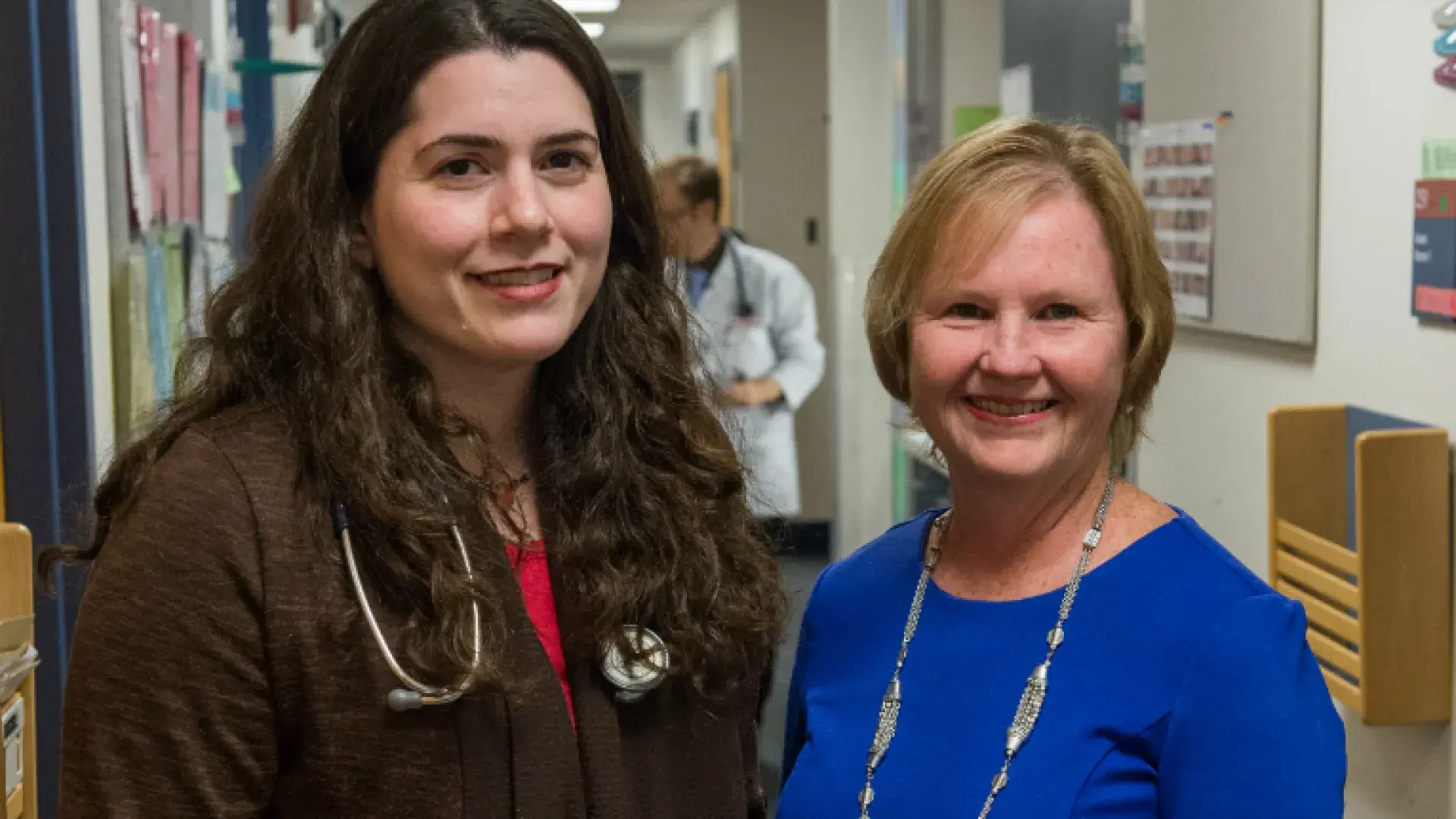 two women stand in a hallway together