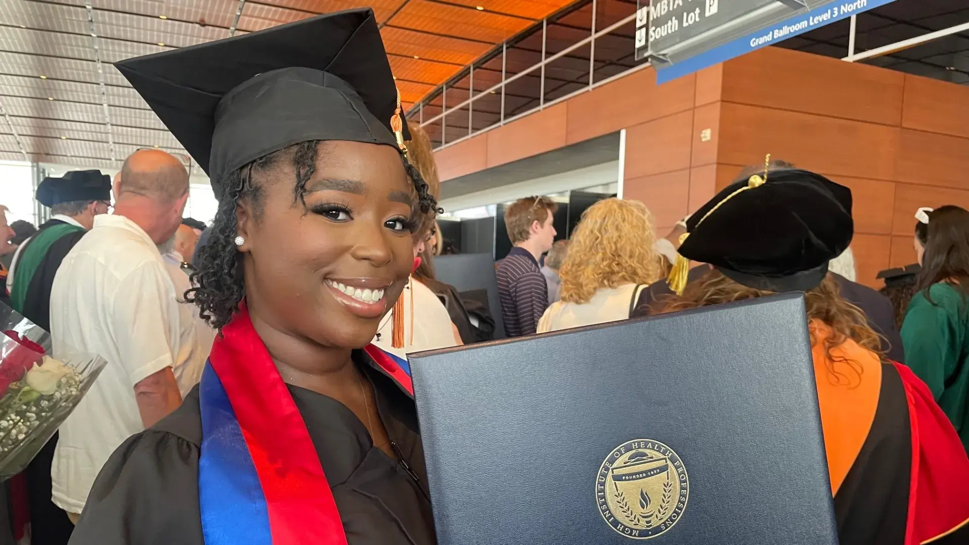 lyn wears a black cap and gown and a red and blue scarf