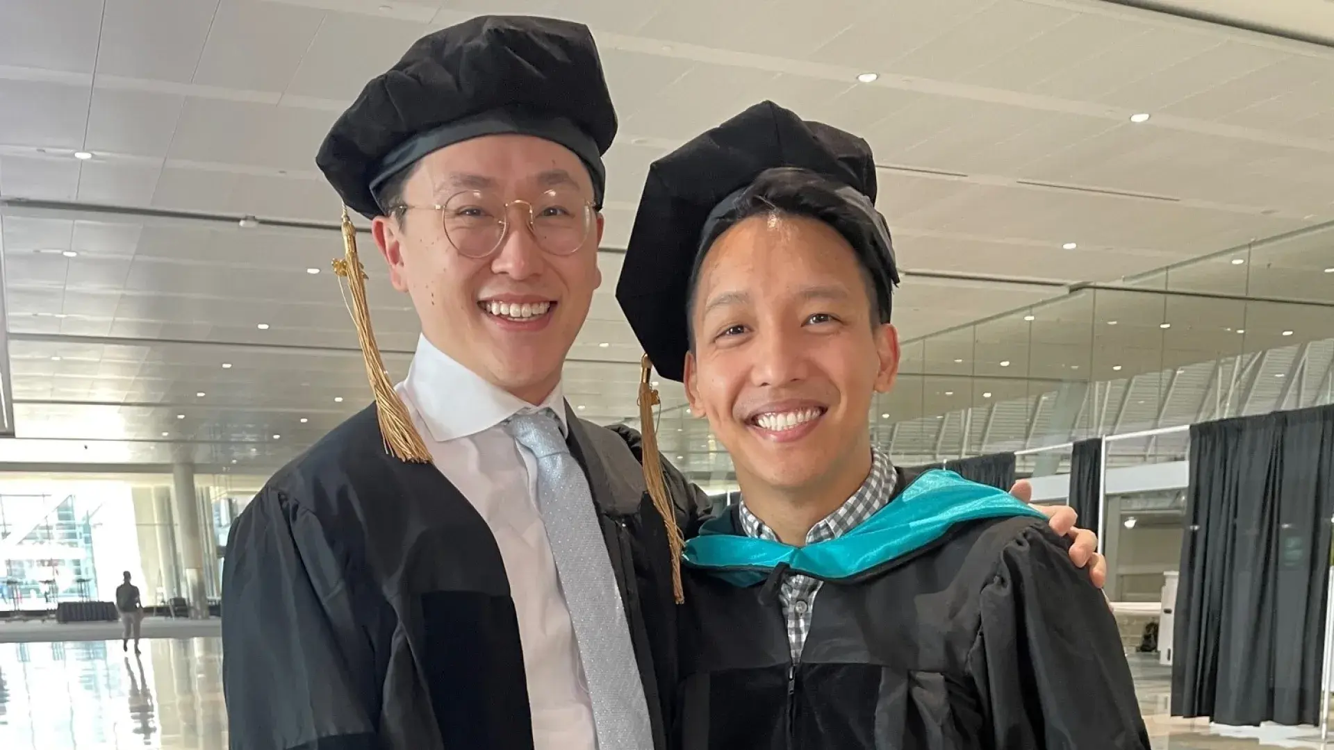 the two men stand in their academic regalia 