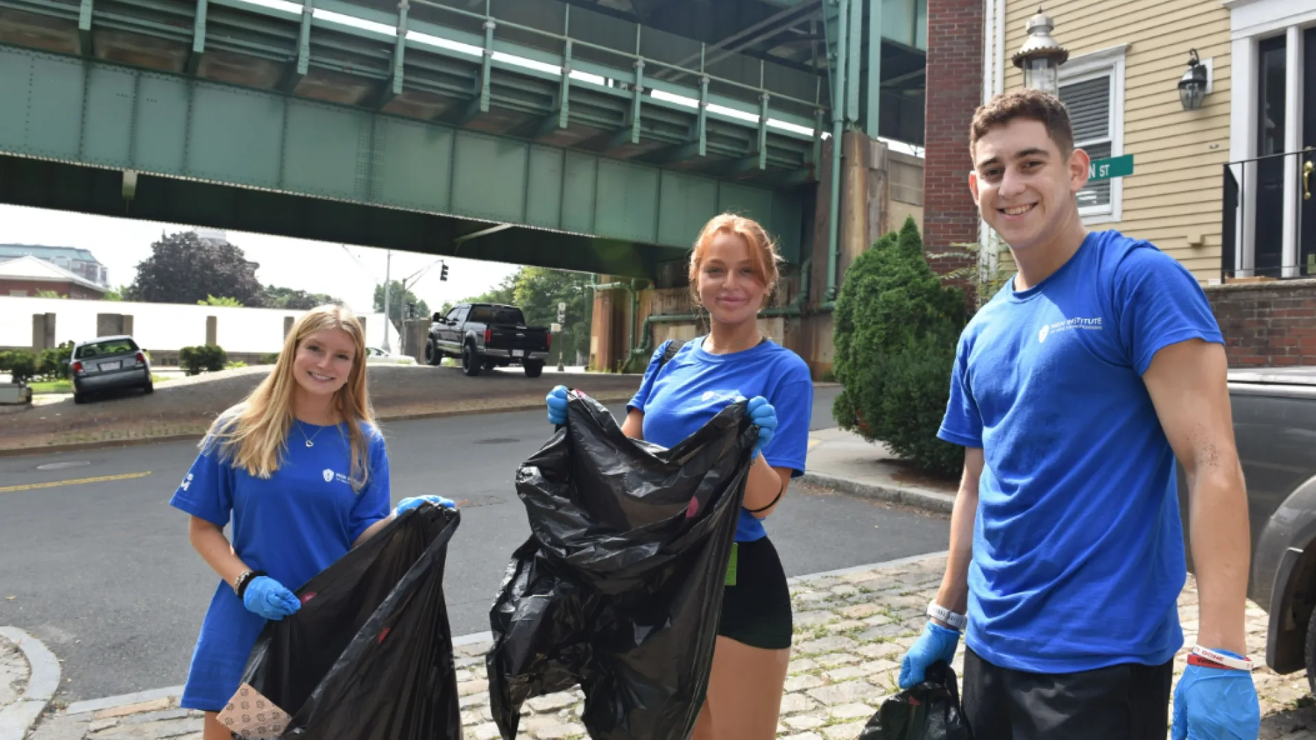 Three students hold trash bags under the Tobin