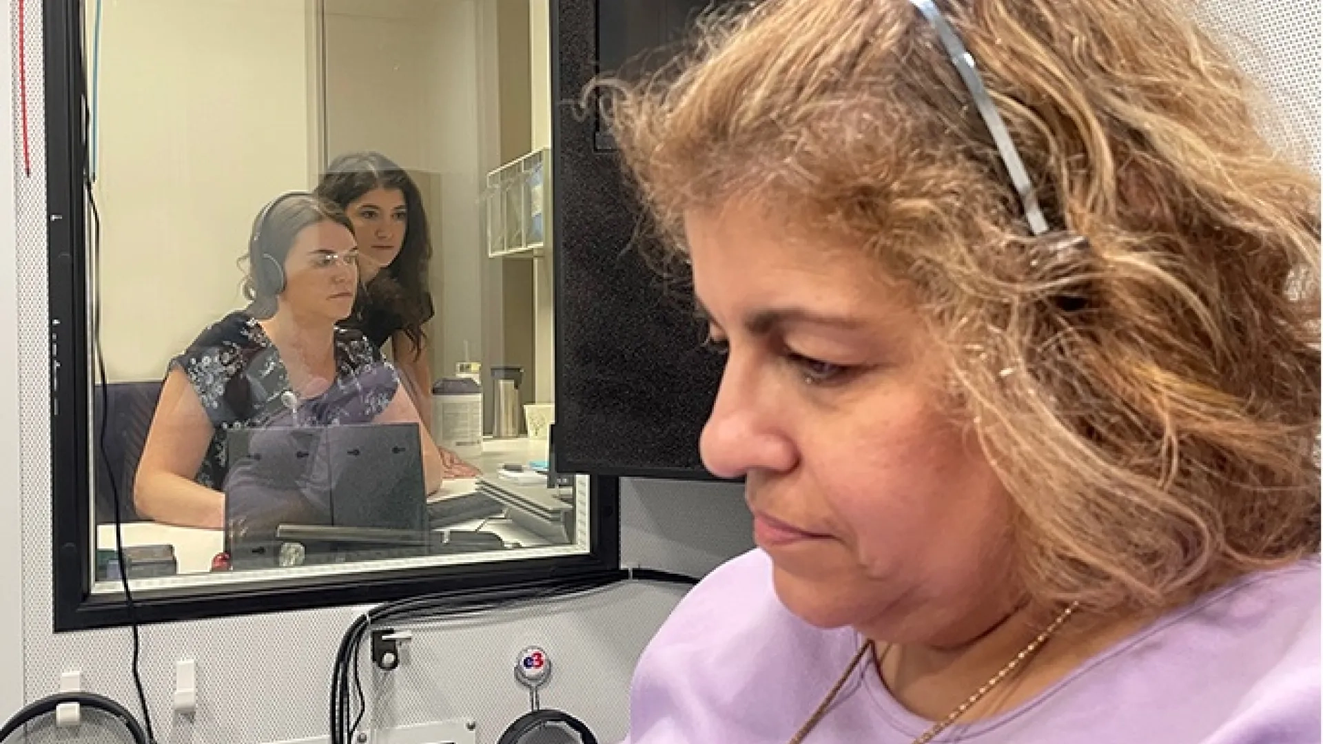 AuD students observing a hearing test conducted in a soundproof booth as part of their hands-on training.
