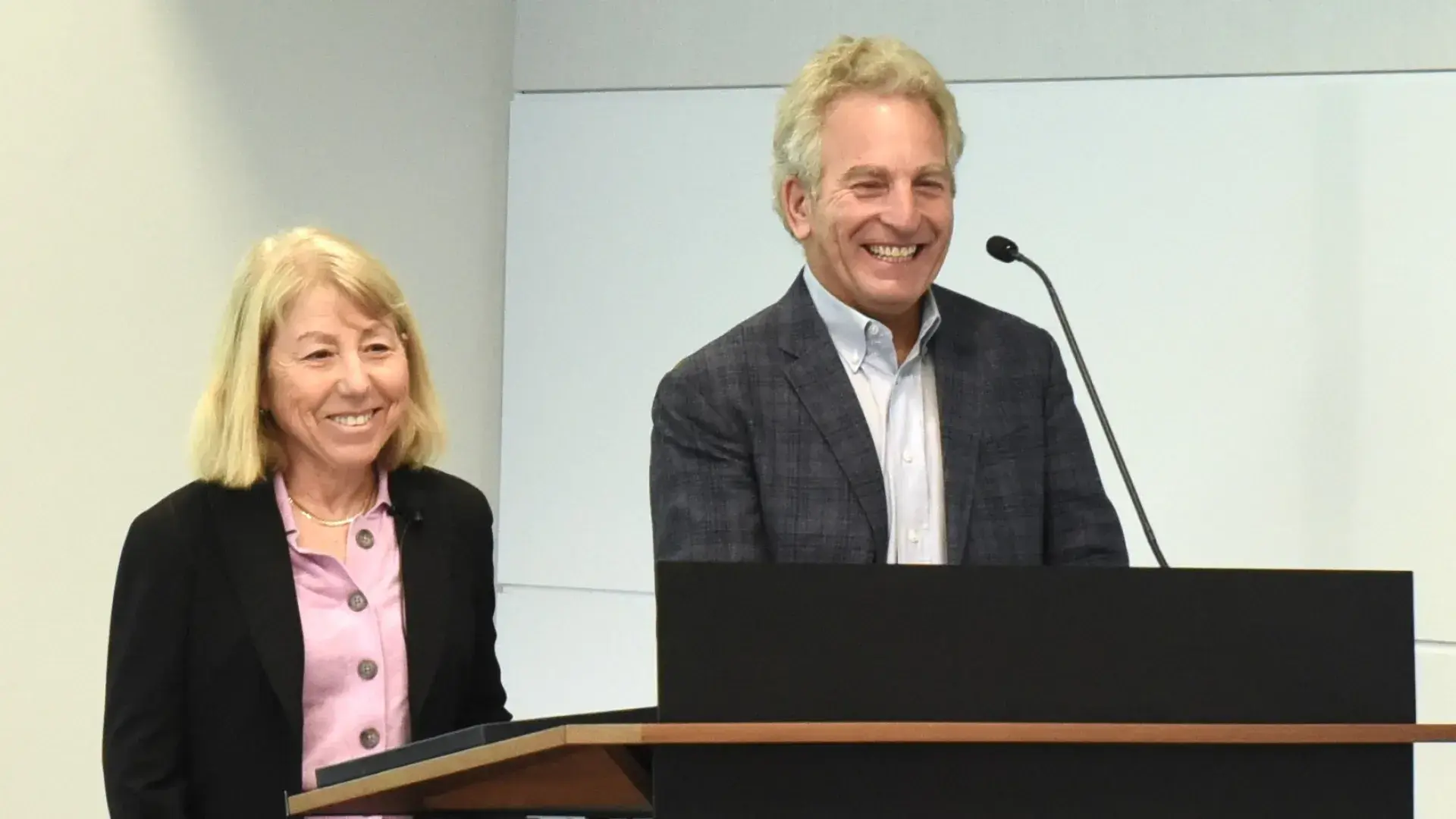 Two people smiling standing at podium