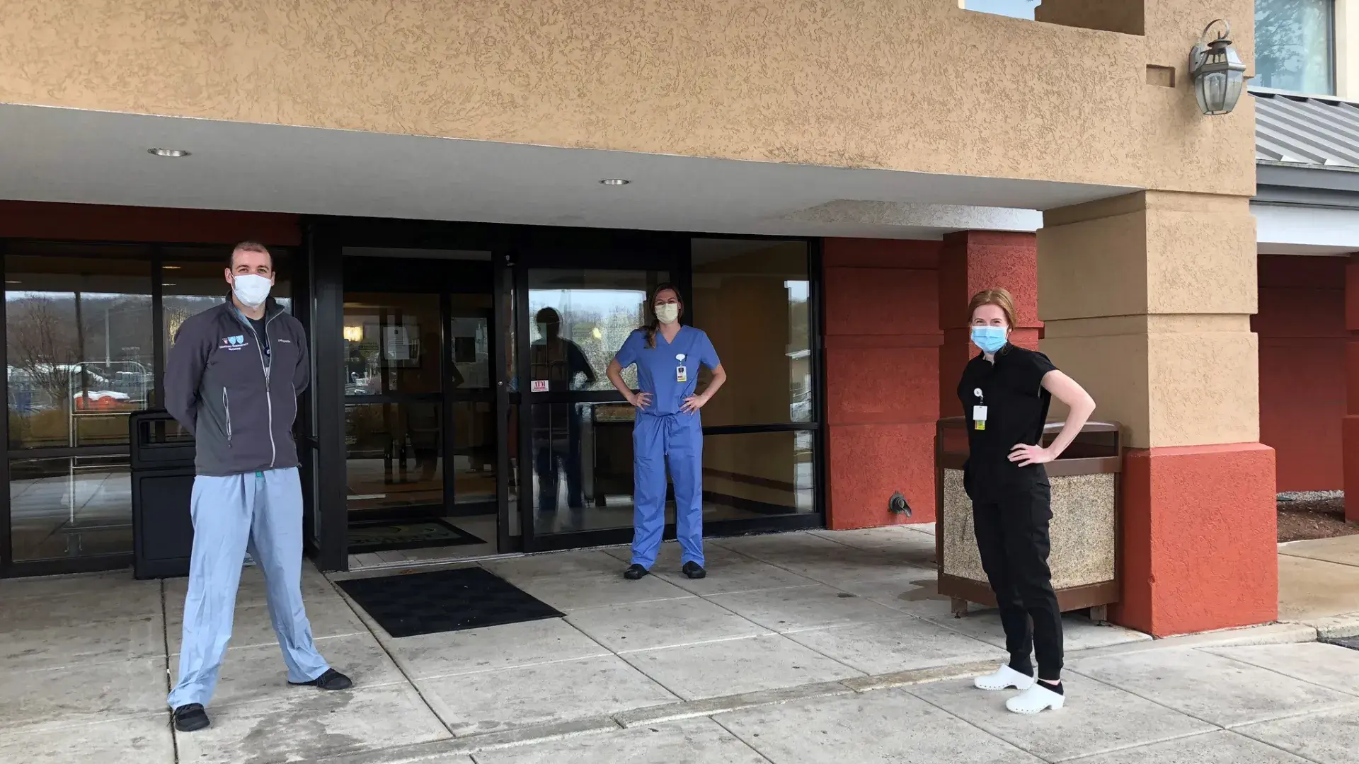 man stands with two women in scrubs