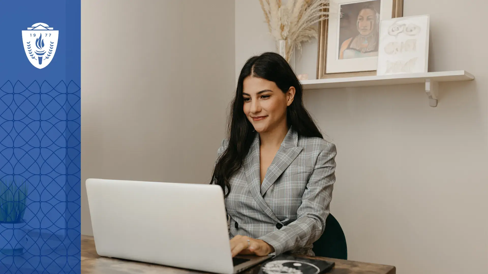 woman in plaid jacket sits at laptop in a cream colored room