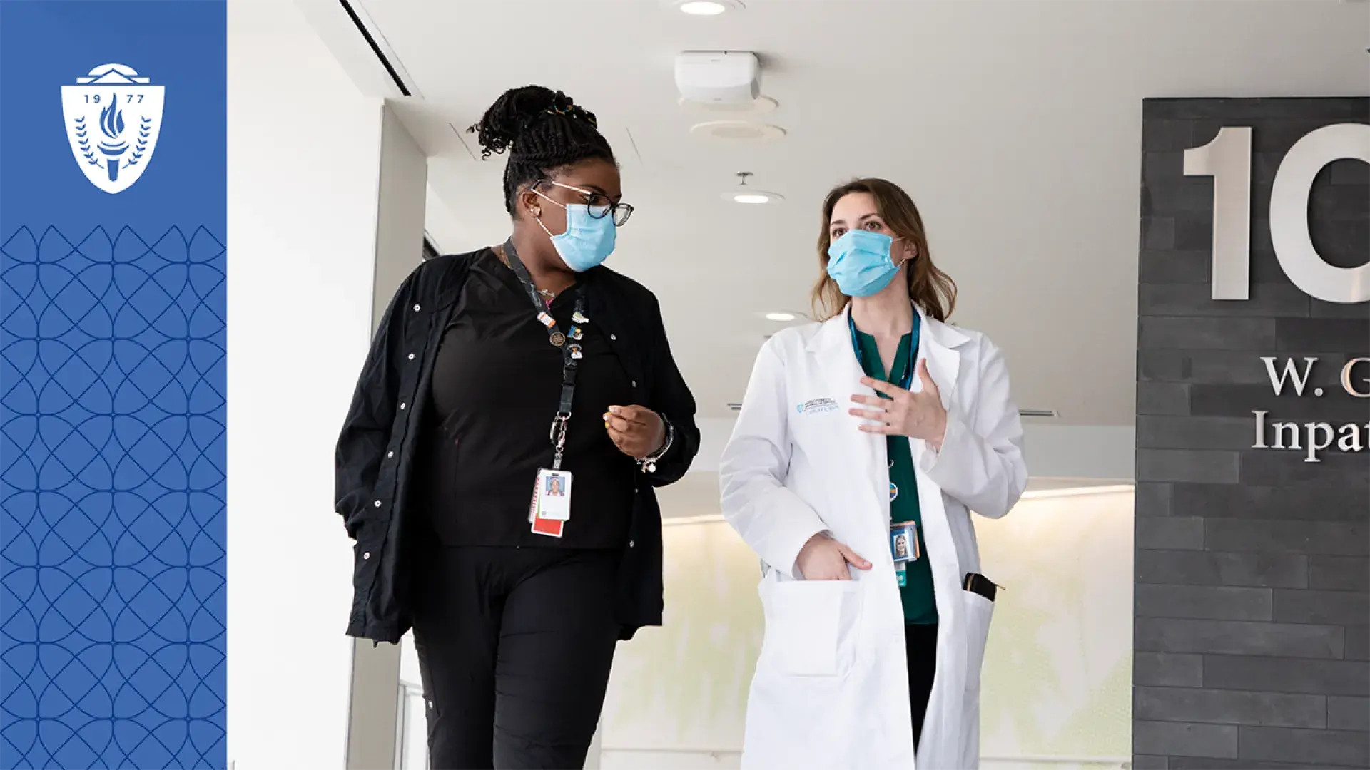  woman in white lab coat walking with another woman in the hospital