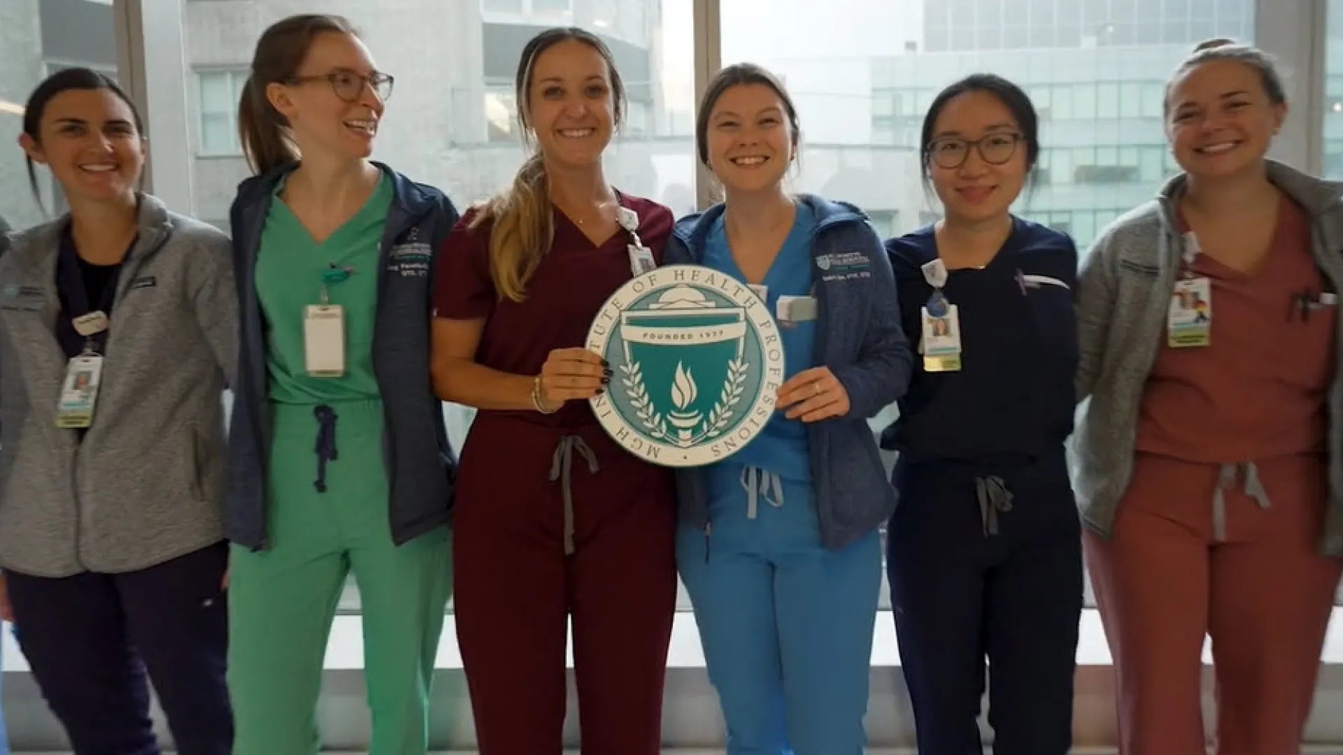group of people in scrubs standing and holding the University's seal