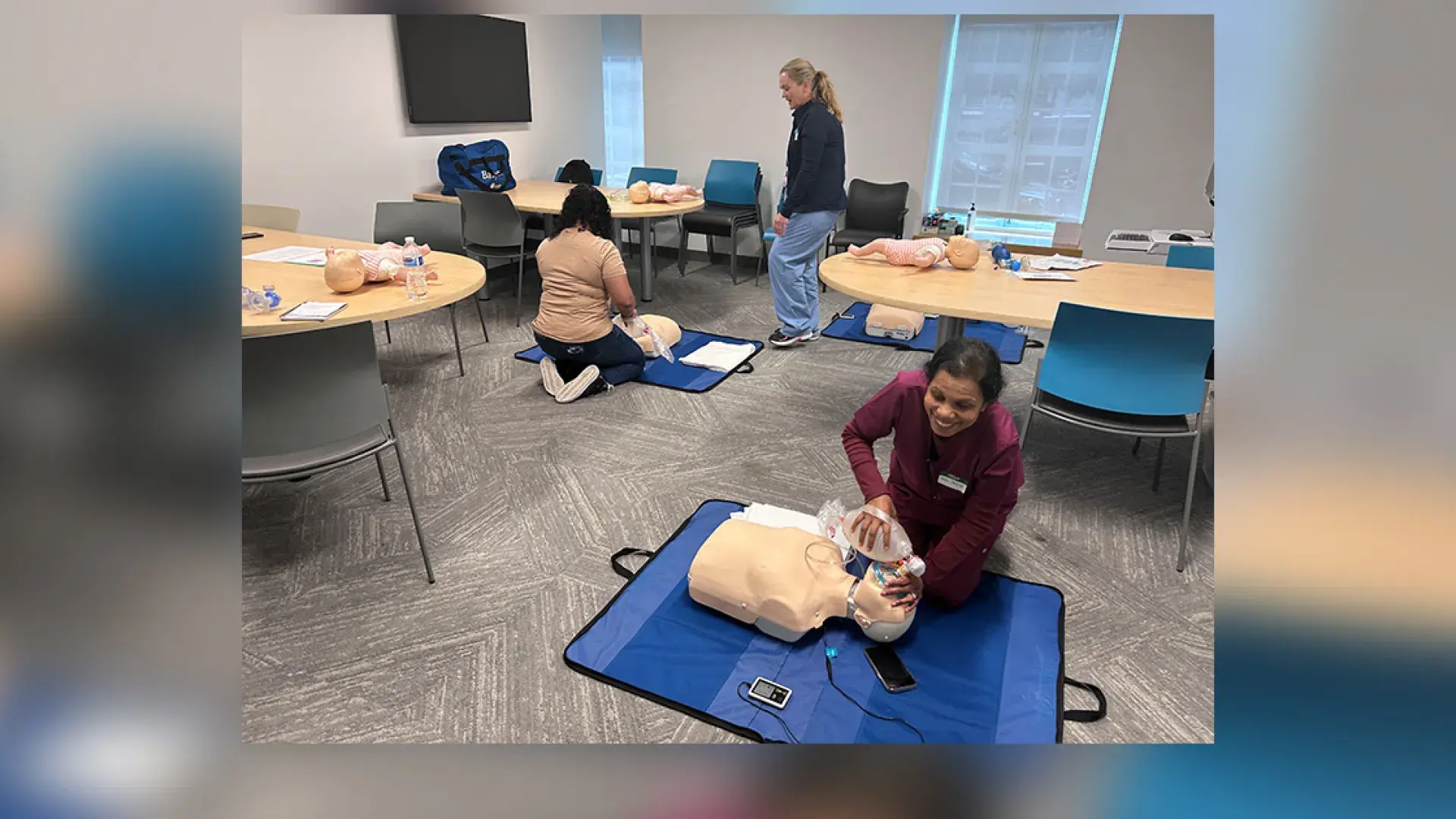 woman kneels in front of a manikin torso on the floor