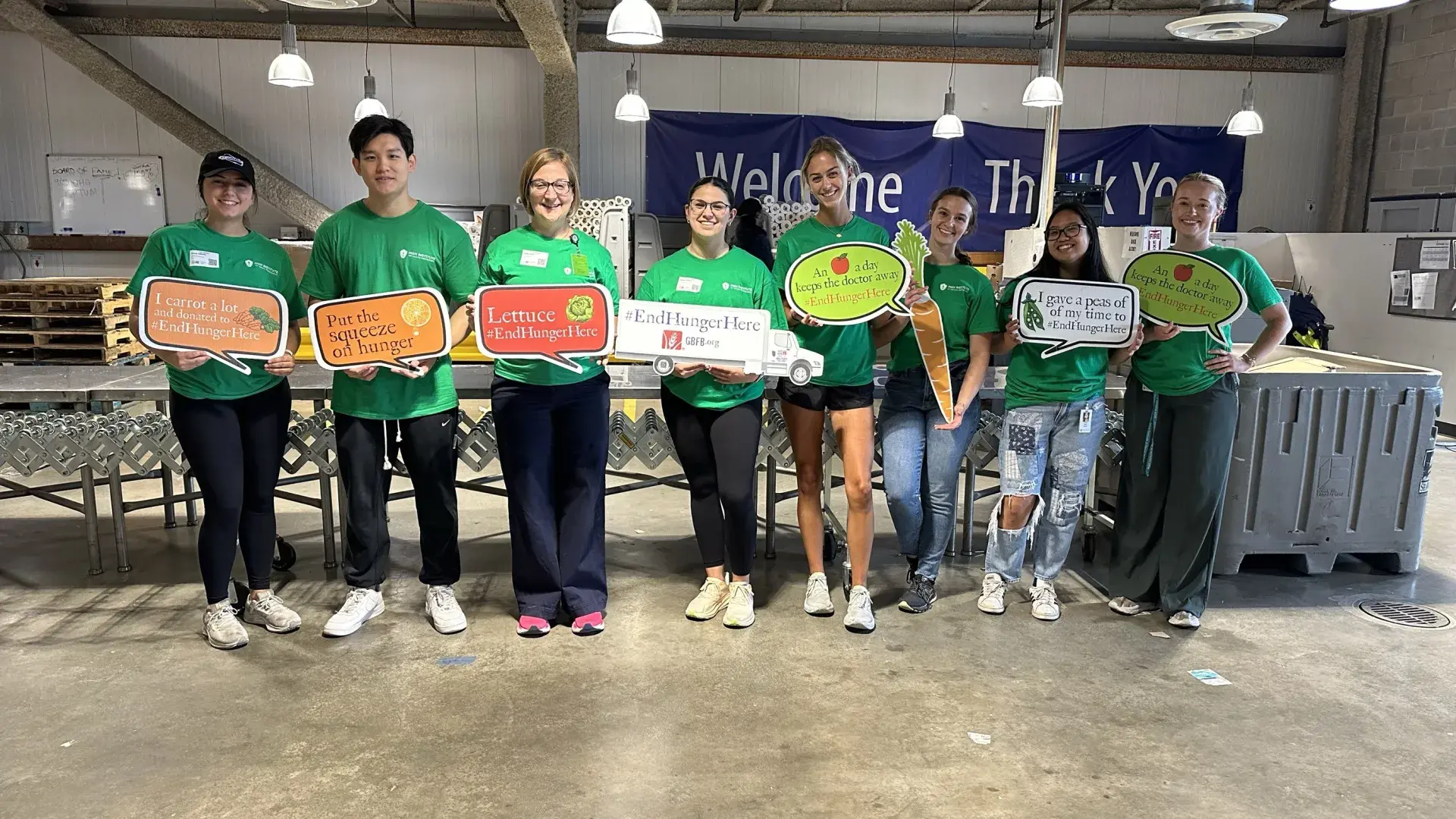 Eight people pose holding signs about food
