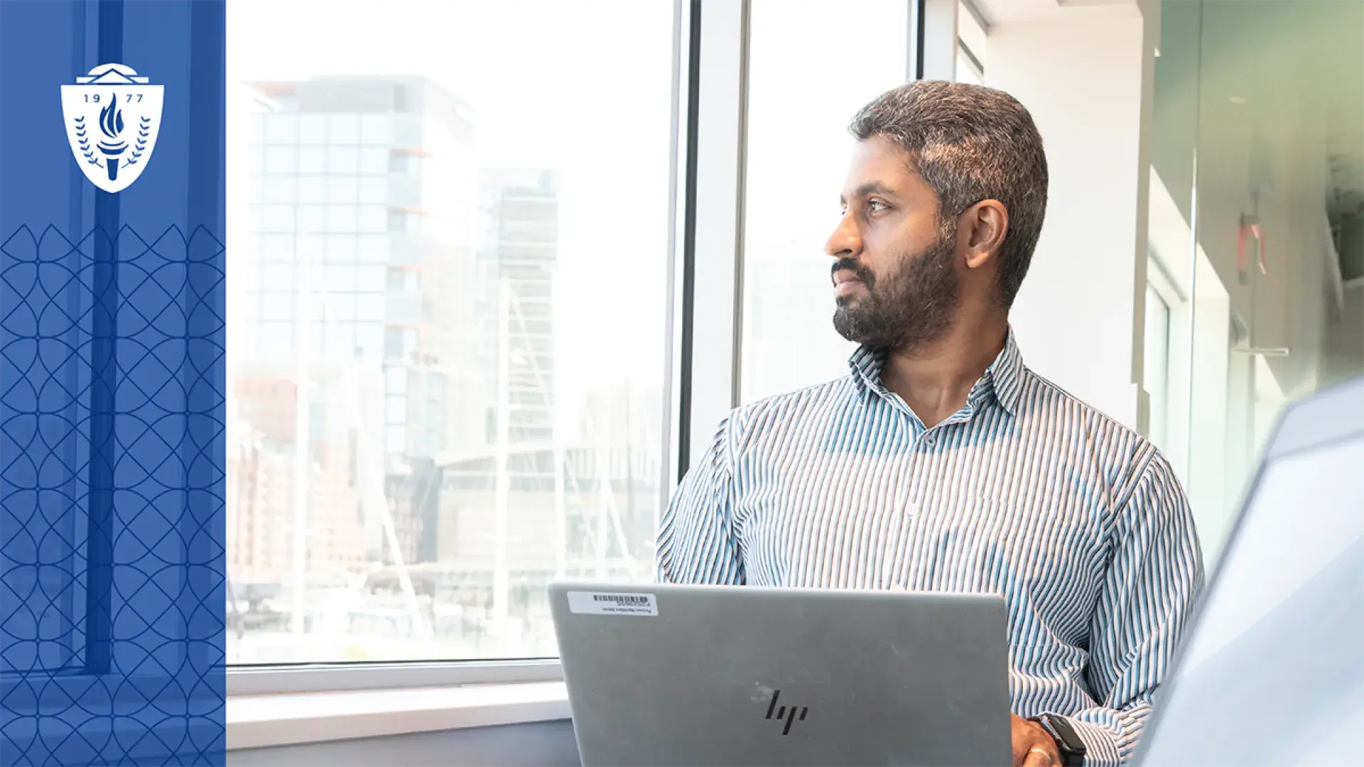 man at laptop looks out window