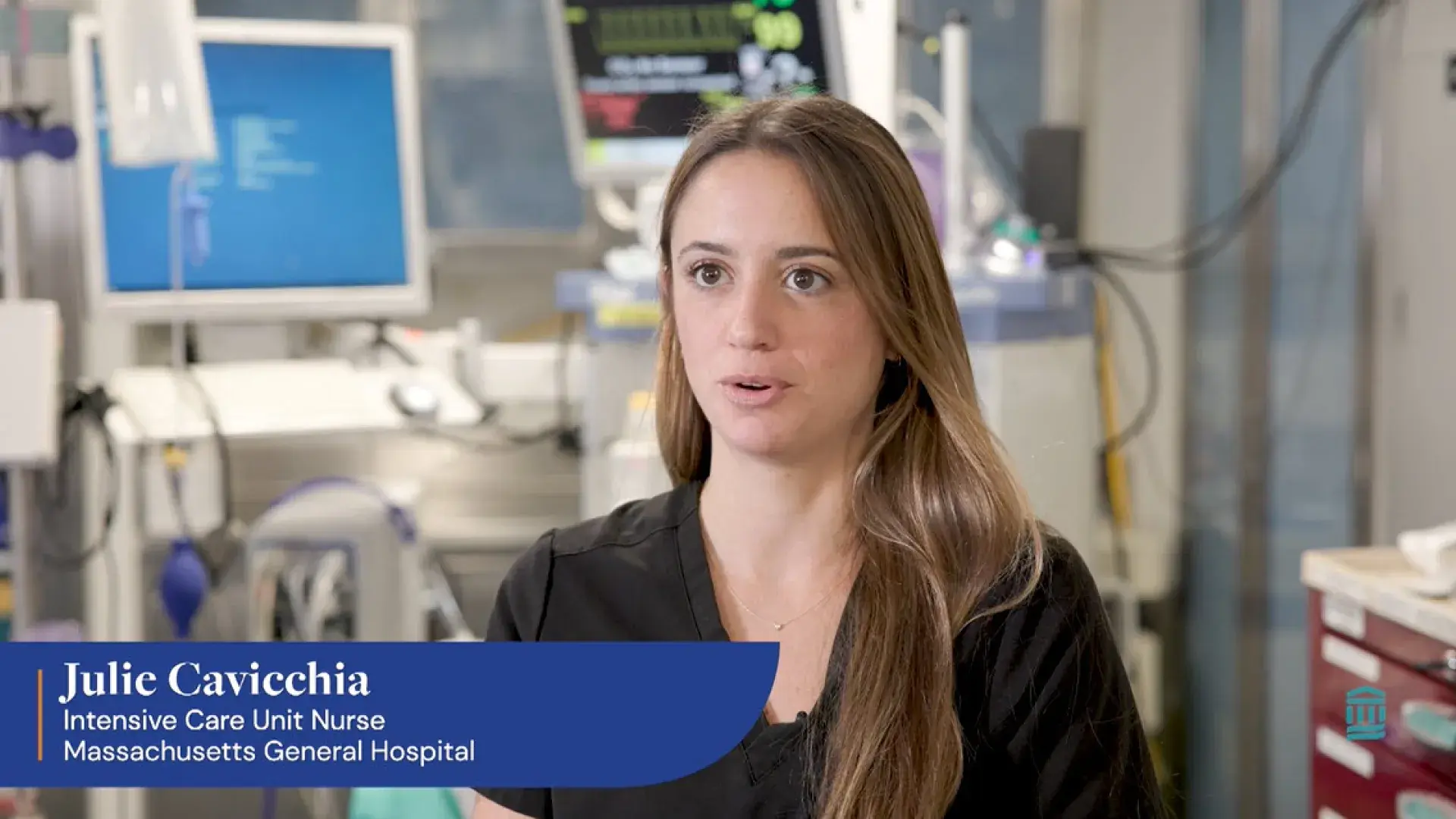 woman with long hair in scrubs talks in a hospital room