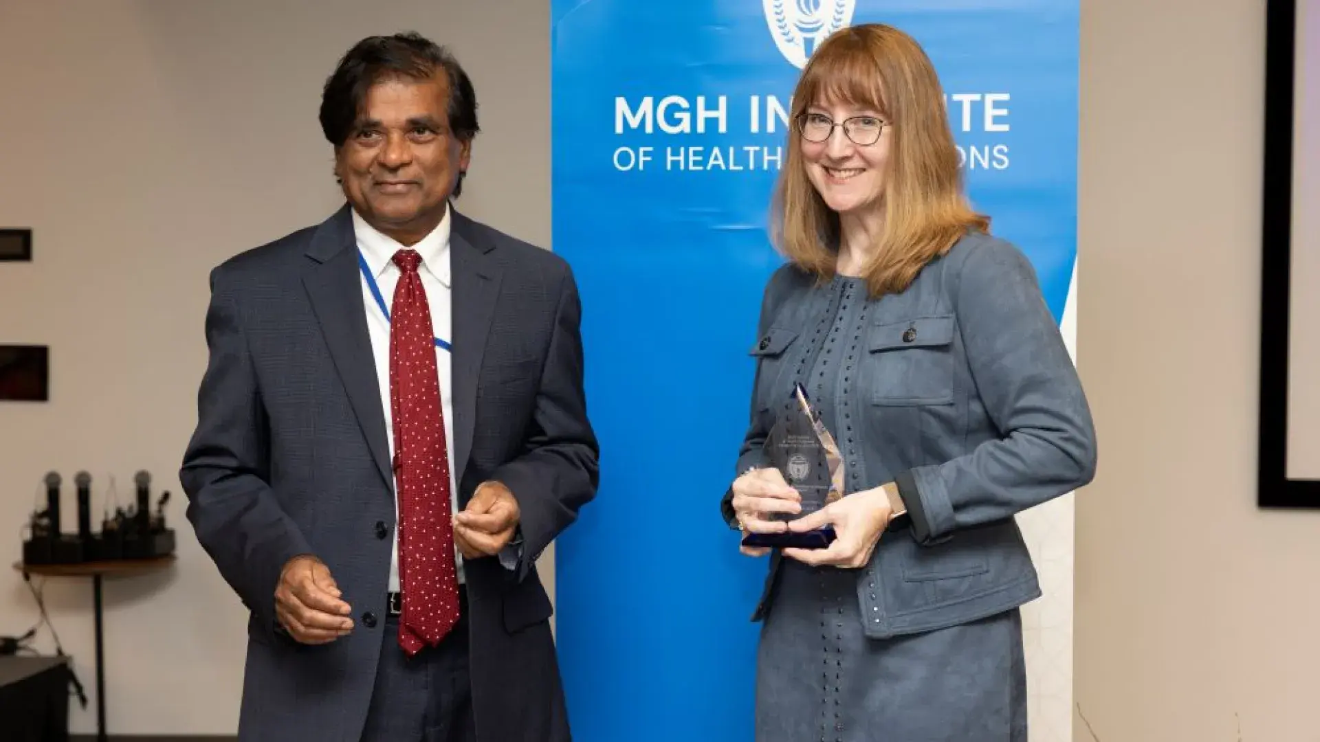 man and woman stand in front of MGH banner with award