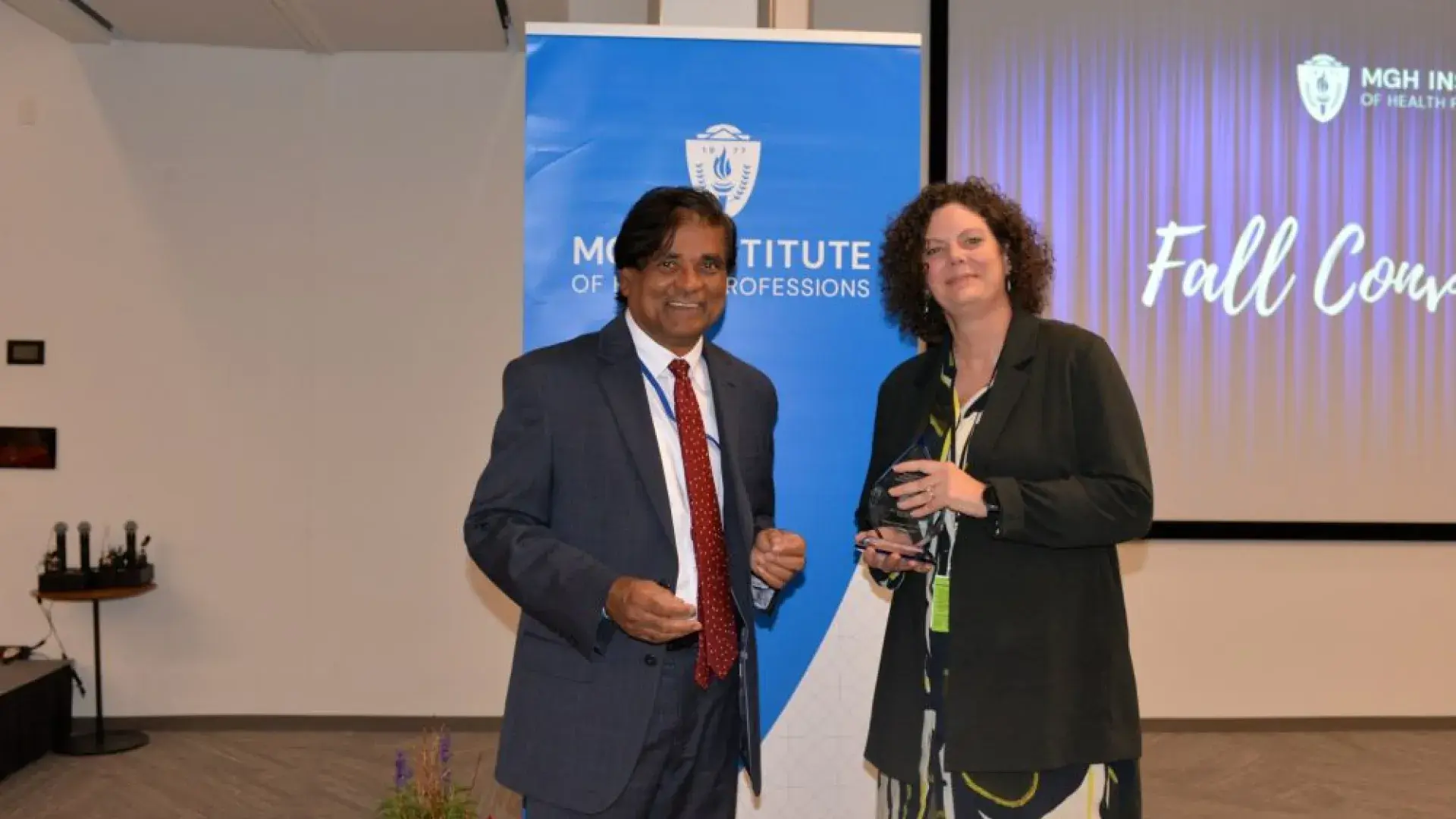 man and woman stand in front of MGH banner with award