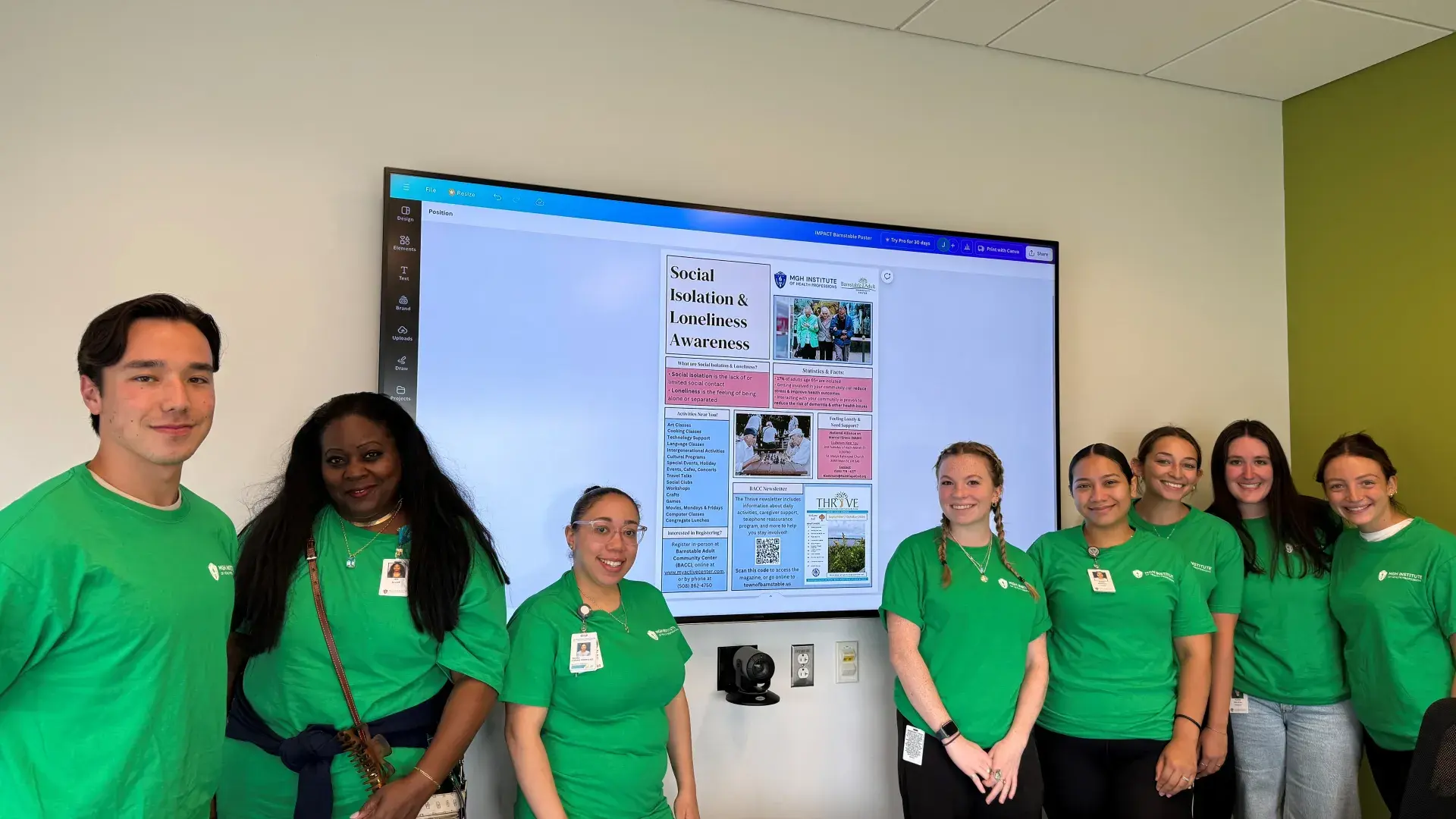 Eight people pose in front of a digital screen that has information on social isolation and loneliness awareness