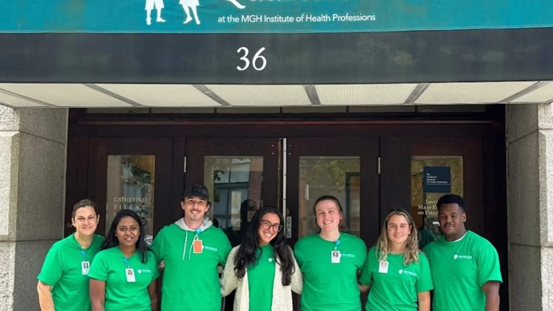 A group poses in the entryway of a building with an awning that has the words, The Children's Quarters and the number 36