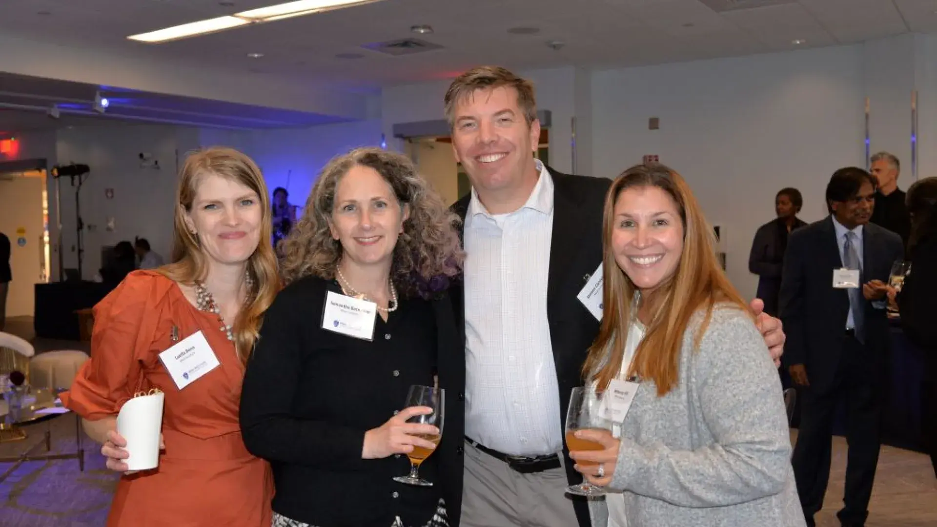 A group of attendees smiling and enjoying drinks during the MGH Institute of Health Professions healthcare networking event.