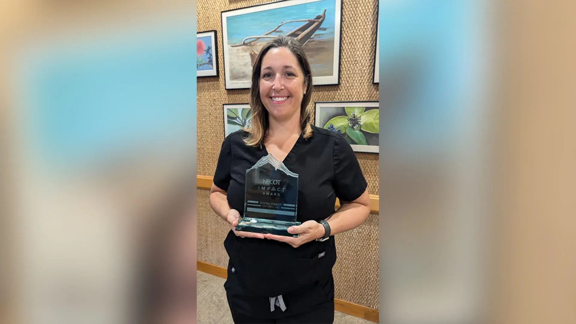 A woman holds an acrylic award with the words NBCOT Impact Award engraved on it