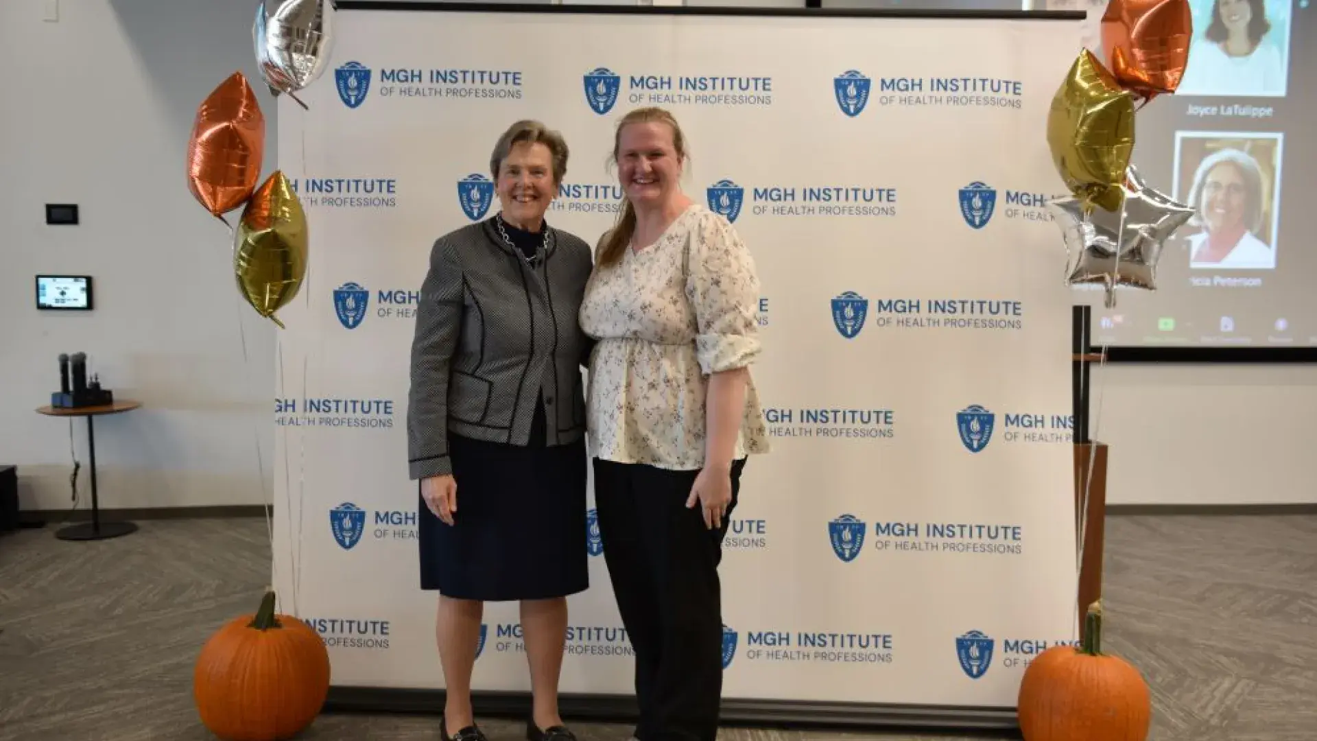 two women stand in front of MGH banner