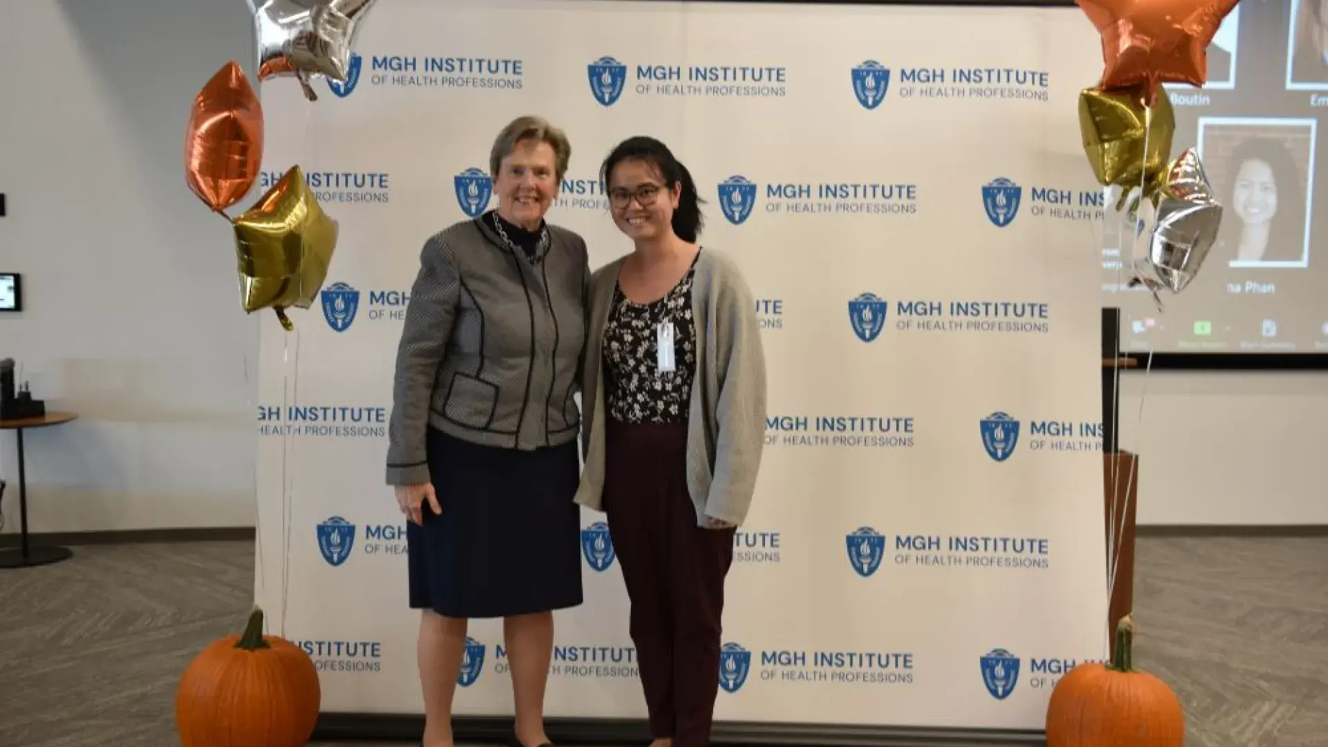 two women stand in front of MGH banner