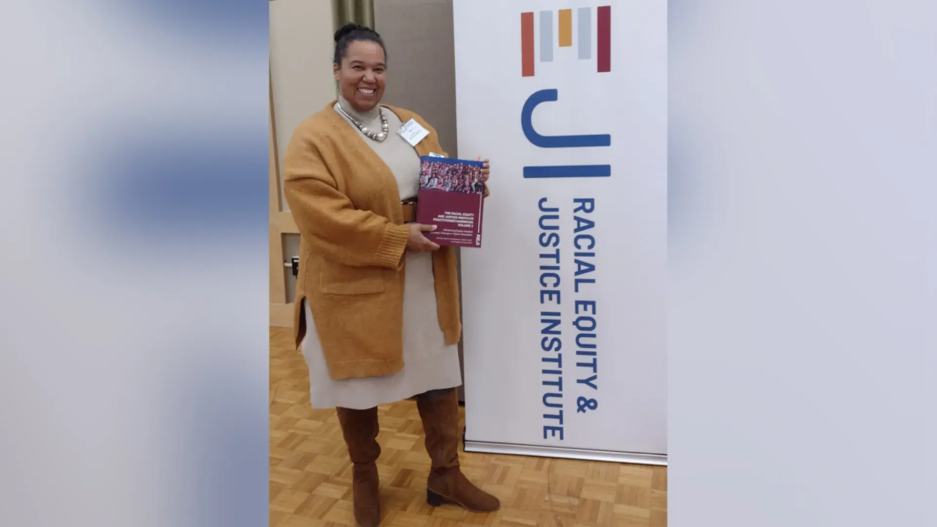 A woman stands in front of a sign holding a book