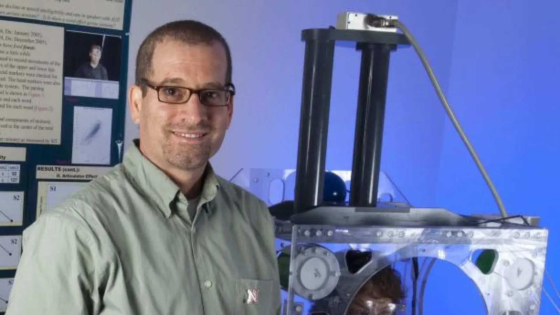 A man poses next to a machine