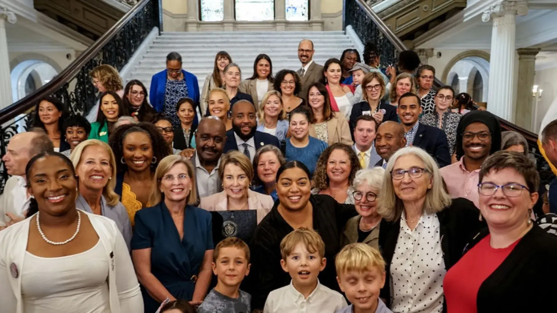 A large group of people stand in front of a wide staircase